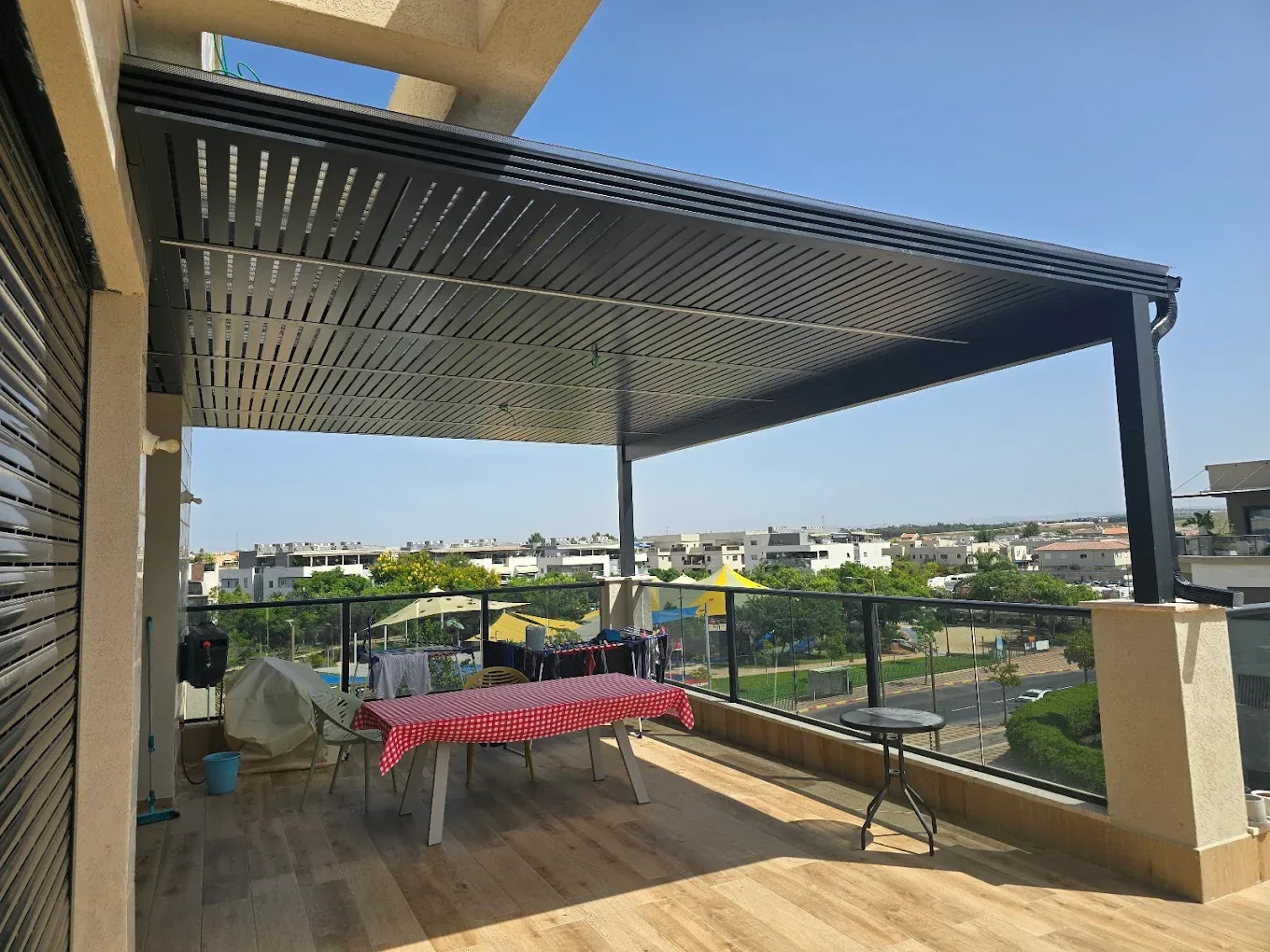 פרגולה כהה במרפסת עם שולחן ופינת ישיבה