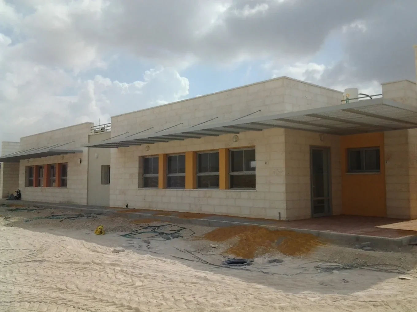 קירוי בהיר צמוד לקיר מבנה ציבורי