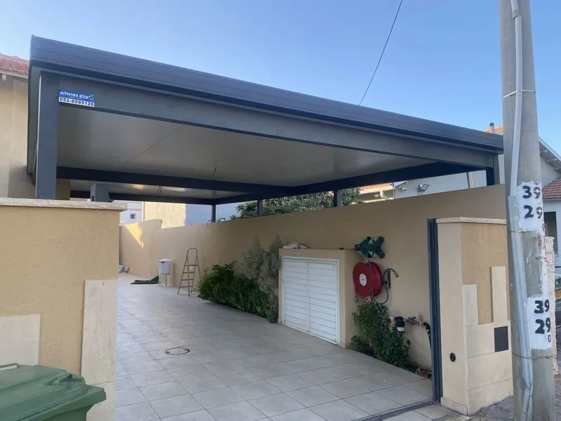 פרגולה כהה מעל מעבר מקורה בכניסה לבית