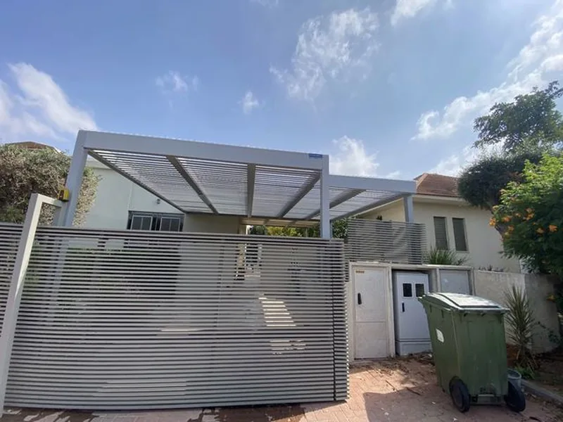פרגולה לבנה לחניה מאחורי שער שלבים אפור