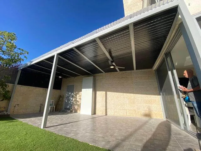 פרגולה כהה על עמודים בחצר במהלך התקנה