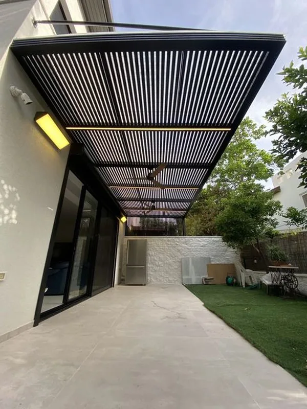 פרגולה כהה עם רפפות ופסי תאורה לאורך הבית